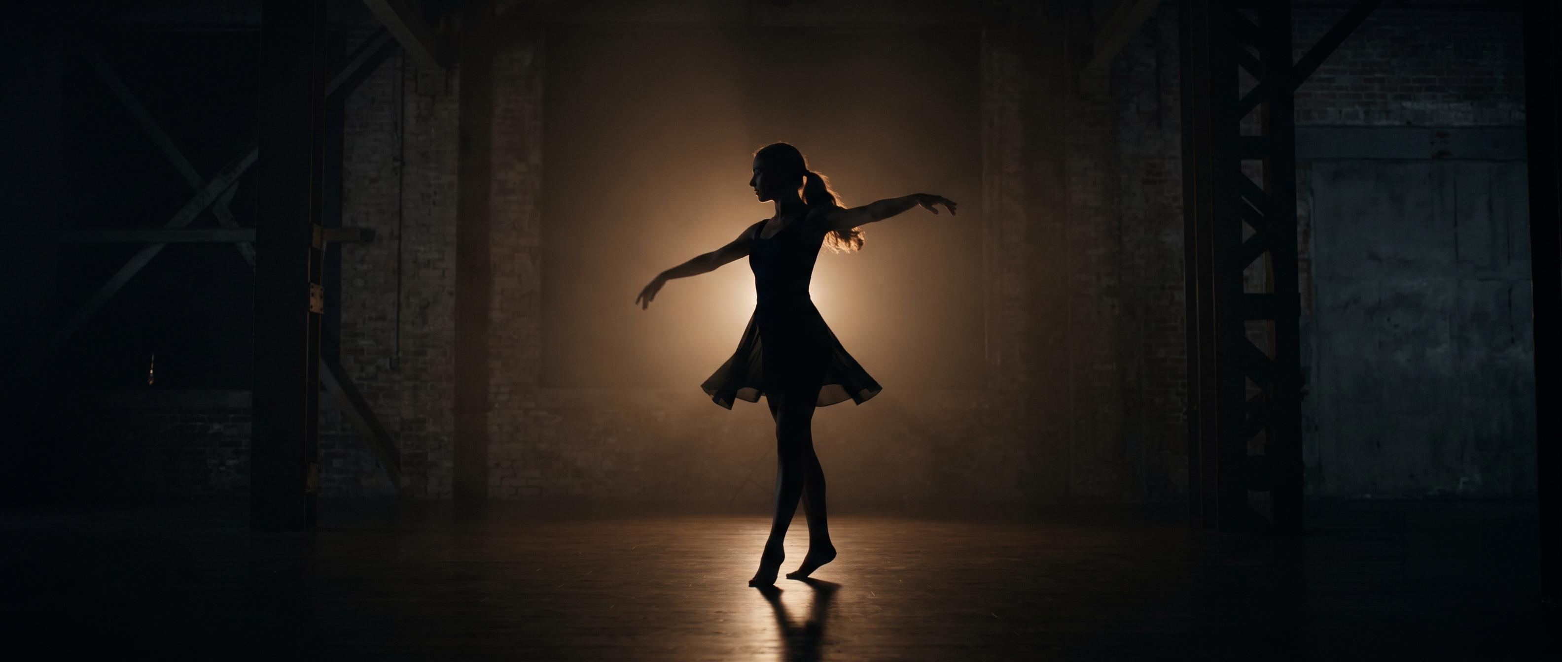 Performer captured as a silhouette against a single backlight in a dark room